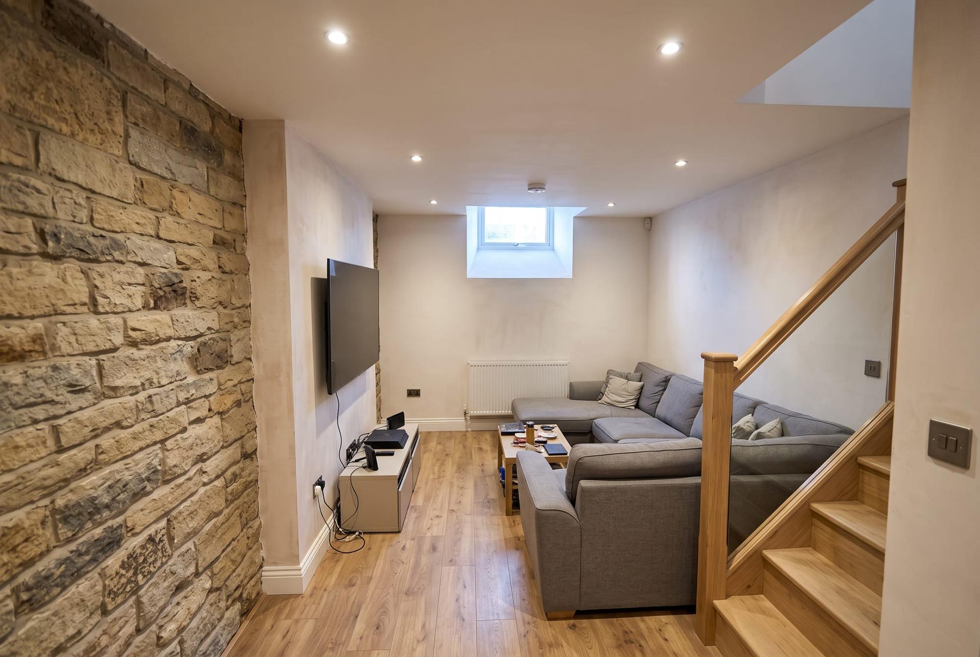 A cellar converted to a snug with one wall of exposed stone and a new staircase