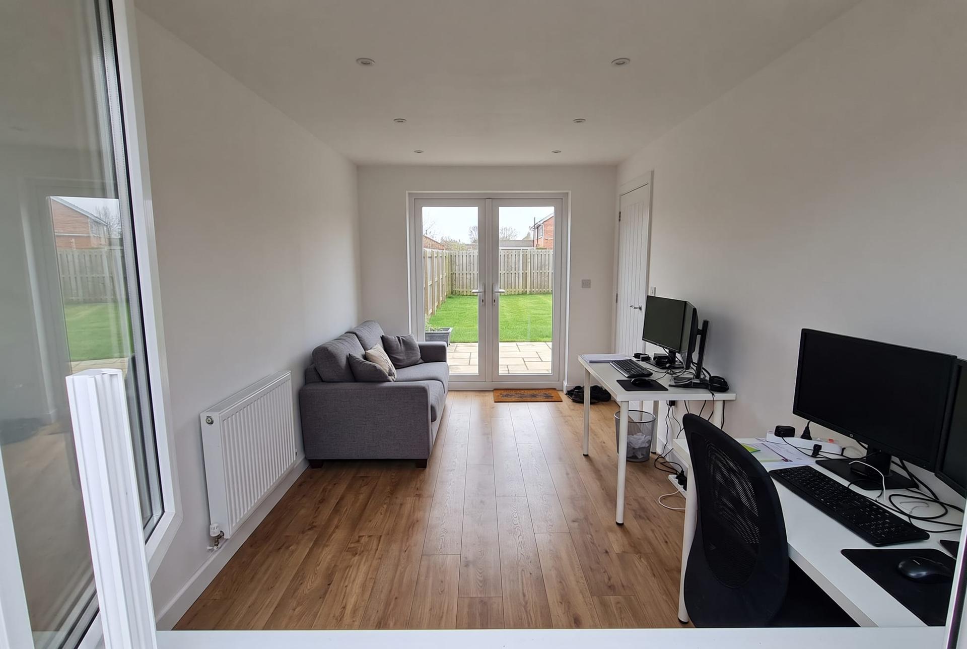 A garage converted to a home office with a window at the front and French doors to the garden