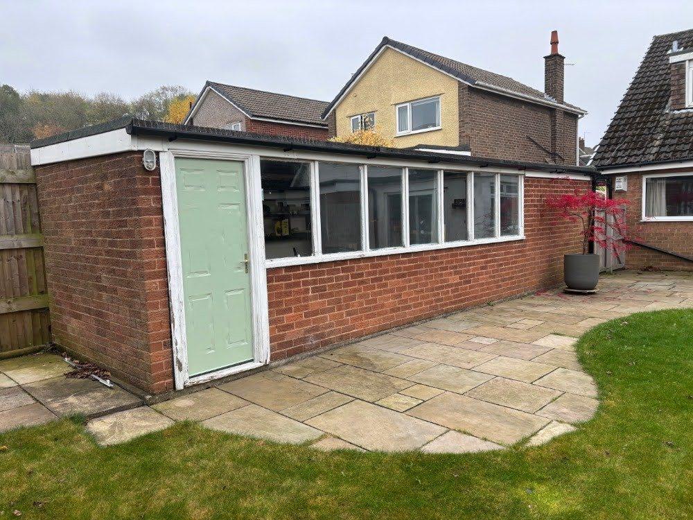 The garage before: green up-and-over door and a run of old windows